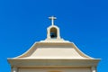 Exterior view of a top of small Catholic church with bell tower, one bell and cross under blue sky Royalty Free Stock Photo