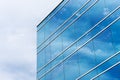 Exterior view of typical blue glass facade of generic modern office building. Sky reflection