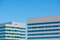 Exterior view of upper floors of two modern office building towers. Blue sky