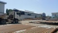 Exterior view of a very large and spacious workshop and pipes arranged and car trailers in a large field