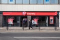 Exterior of Virgin Money branch on a high street with people walking past and customers using entrance