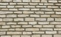 Exterior wall made of long beige natural stones bricks on gray concrete.