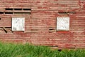 Exterior wall on old wood red barn with boarded up windows