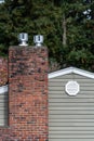 Exterior wall of suburban house, old brick chimney with chimney vents, attic fan exhaust vent on wall Royalty Free Stock Photo