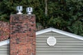 Exterior wall of suburban house, old brick chimney with chimney vents, attic fan exhaust vent on wall Royalty Free Stock Photo