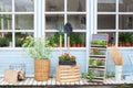 Exterior wooden porch of house with green plants and flowers in box. Street patio. Facade home with garden tools, wicker basket a