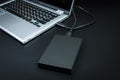 An external hard drive connected to the laptop with a usb cable on a black background Royalty Free Stock Photo