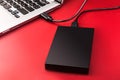 An external hard drive connected to the laptop with a usb cable on a red background Royalty Free Stock Photo