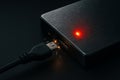 External hard drive with pulsing red light and data cable sparks Royalty Free Stock Photo
