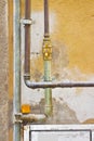 External metal and copper gas pipes, in front of an old plaster wall, with yellow gate valve Royalty Free Stock Photo