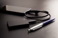 External portable SSD connected to smartphone on a dark gradient background next to fountain pen. Portable Solid State Drive. The Royalty Free Stock Photo