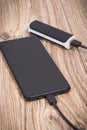 External powerbank using to charge empty battery of black smartphone