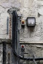 External security light mounted on an old shabby external wall with messy wiring and barbed wire