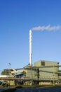 External view of large modern biomass cogeneration wood chip power plant with tall steam chimney