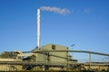 External view of large modern biomass cogeneration wood chip power plant with tall steam chimney