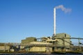 External view of large modern biomass cogeneration wood chip power plant with tall steam chimney