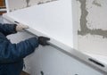 External wall foam board insulation. A building contractor is installing rigid polystyrene, styrofoam insulation to the house wall