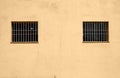 External yellow wall with two small windows with bars. Royalty Free Stock Photo
