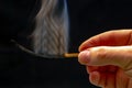 Extinct and fuming wooden match on a dark background close-up. smoke from a burning tree