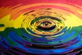 The Gay Pride Extinction Rebellion flag and logo reflected in circular waves from a water splash along with two falling droplets o Royalty Free Stock Photo