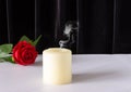 An extinguished candle and a red rose on a black background. The concept of mourning, condolences, funerals Royalty Free Stock Photo