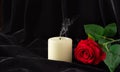 An extinguished candle and a red rose on a black background. The concept of mourning, condolences, funerals Royalty Free Stock Photo