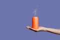 Extinguished candle with smoke in female hand isolated on Royal Purple background Royalty Free Stock Photo