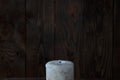 Extinguished big white candle in the dark. On a wooden background. Royalty Free Stock Photo