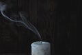 Extinguished big white candle in the dark. On a wooden background. Royalty Free Stock Photo