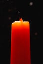 An extinguished orange candle against a dark background in the backlight. Royalty Free Stock Photo