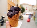 Extra dark creamy chocolate ice cream in waffle cone in hand