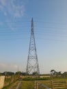 Extra high voltage overhead line tower in the middle of rice fields near a residential area on the island of Lombok, Indonesia