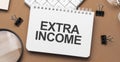 EXTRA INCOME on notepad with pen, glasses and calculator