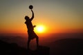 Extra-league volleyball player stands on a stump at the top of a mountain and plays with a volleyball ball in one hand at sunset. Royalty Free Stock Photo