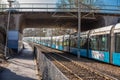 Extra long blue and white commuter train passing under a bridge.. Royalty Free Stock Photo