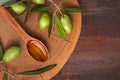 Extra virgin olive oil in wooden spoon with fresh olives on wooden background