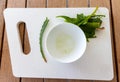 Extraction aloe from the plant, bowl with extracted aloe and plant scraps on white cutting board on wooden table