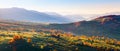 Extraordinary autumn landscape. Green fields with haystacks. Trees covered with orange and crimson leaves. Mountain landscapes. Royalty Free Stock Photo