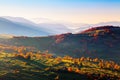 Extraordinary autumn scenery. Green fields with haystacks. Trees covered with orange and crimson leaves. Mountain landscapes.