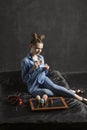 Extraordinary girl in blue shirt drinks coffee and eats muffins on black background in studio. Cupcakes on black tray Royalty Free Stock Photo