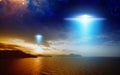 Extraterrestrial aliens spaceship fly above sunset sea Royalty Free Stock Photo