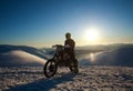 Extreme biker on sport motorcycle on winter snow mountain on sky