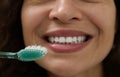 Extreme close-up of the beautiful smile of a woman with clean white teeth, holding a toothbrush near her mouth Royalty Free Stock Photo