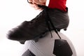 Extreme close-up of caucasian young female player tying shoe lace with foot on soccer ball Royalty Free Stock Photo