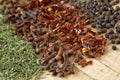 Extreme close up of dried herbs and spices on a wooden cutting board. Macro shot of ground savory, clove, paprika and pepppercorn