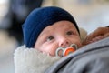 Extreme close up of happy little baby with big eyes looking up with a pacifier and a blue hat Royalty Free Stock Photo