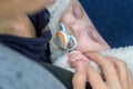 Extreme close up of little baby sleeping with a pacifier and holding mothers hand Royalty Free Stock Photo