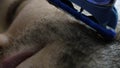 Extreme close up man cheek shaving stubble with a shaving machine. Daily face care