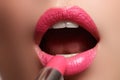 Extreme close up on model applying pink lipstick. Makeup. Professional fashion retro make-up. Red lipstick.