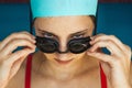 Extreme close-up shot of a Caucasian girl head with a swimming cap and hands putting swimming goggles, preparing for Royalty Free Stock Photo